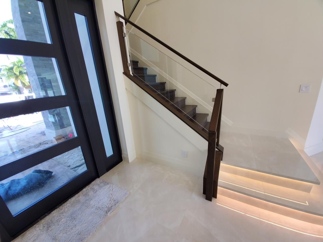 Staircase with glass railing and lit steps