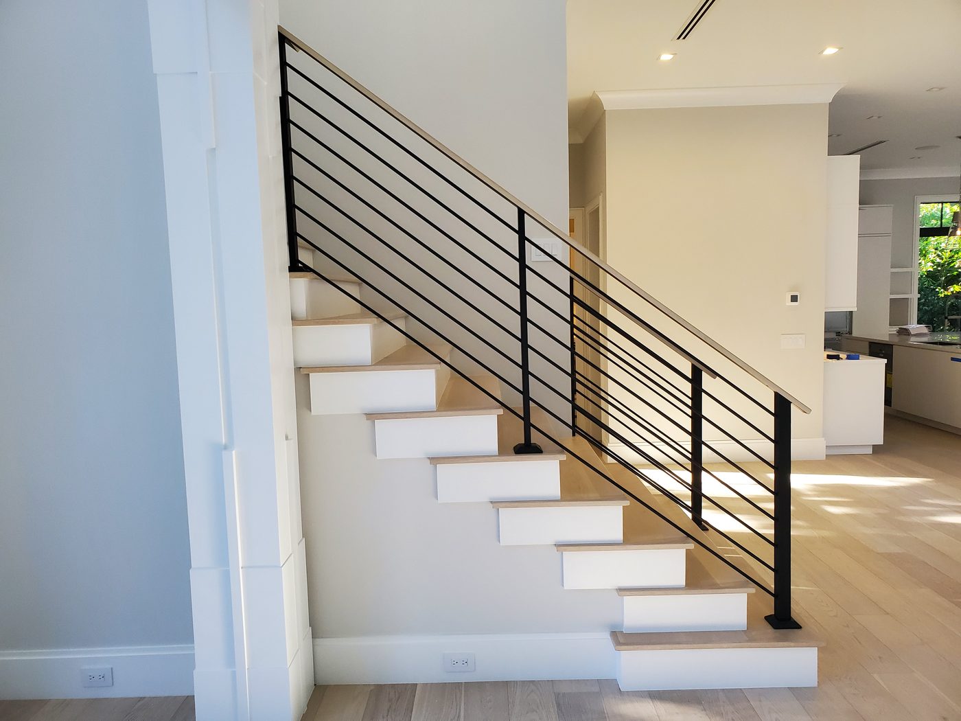 Staircase with horizontal metal rods and oak handrail