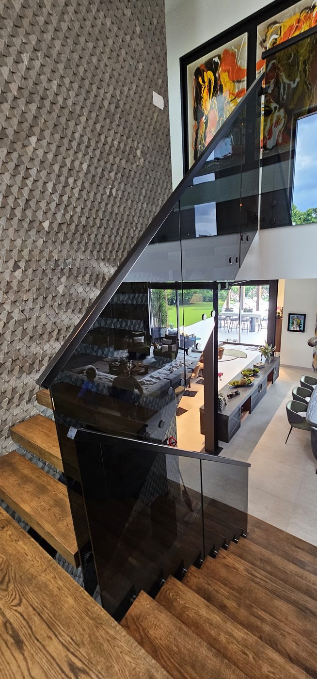View down a floating staircase with smoked-glass railing