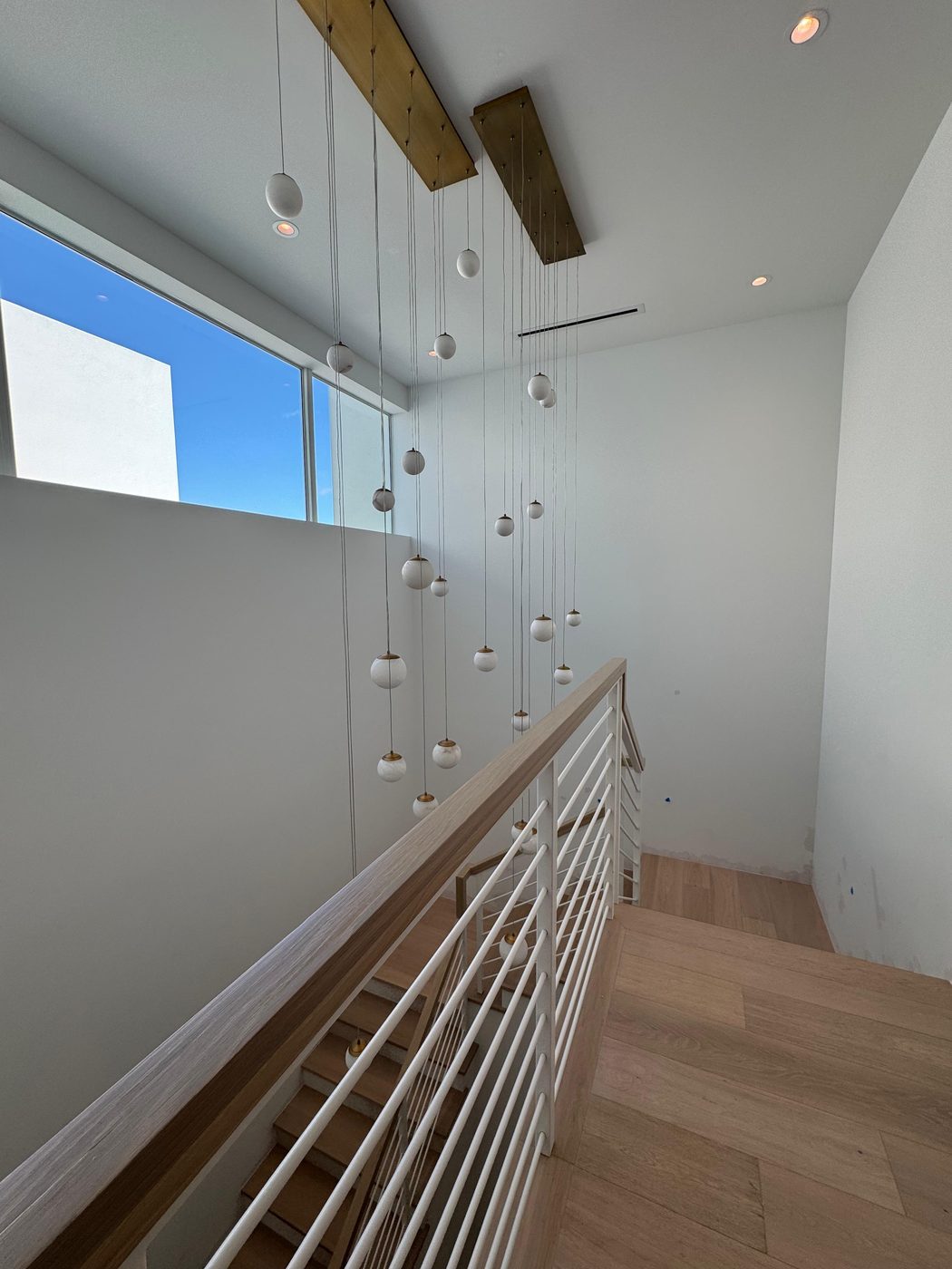 White rod railing with wood handrail over a stairwell
